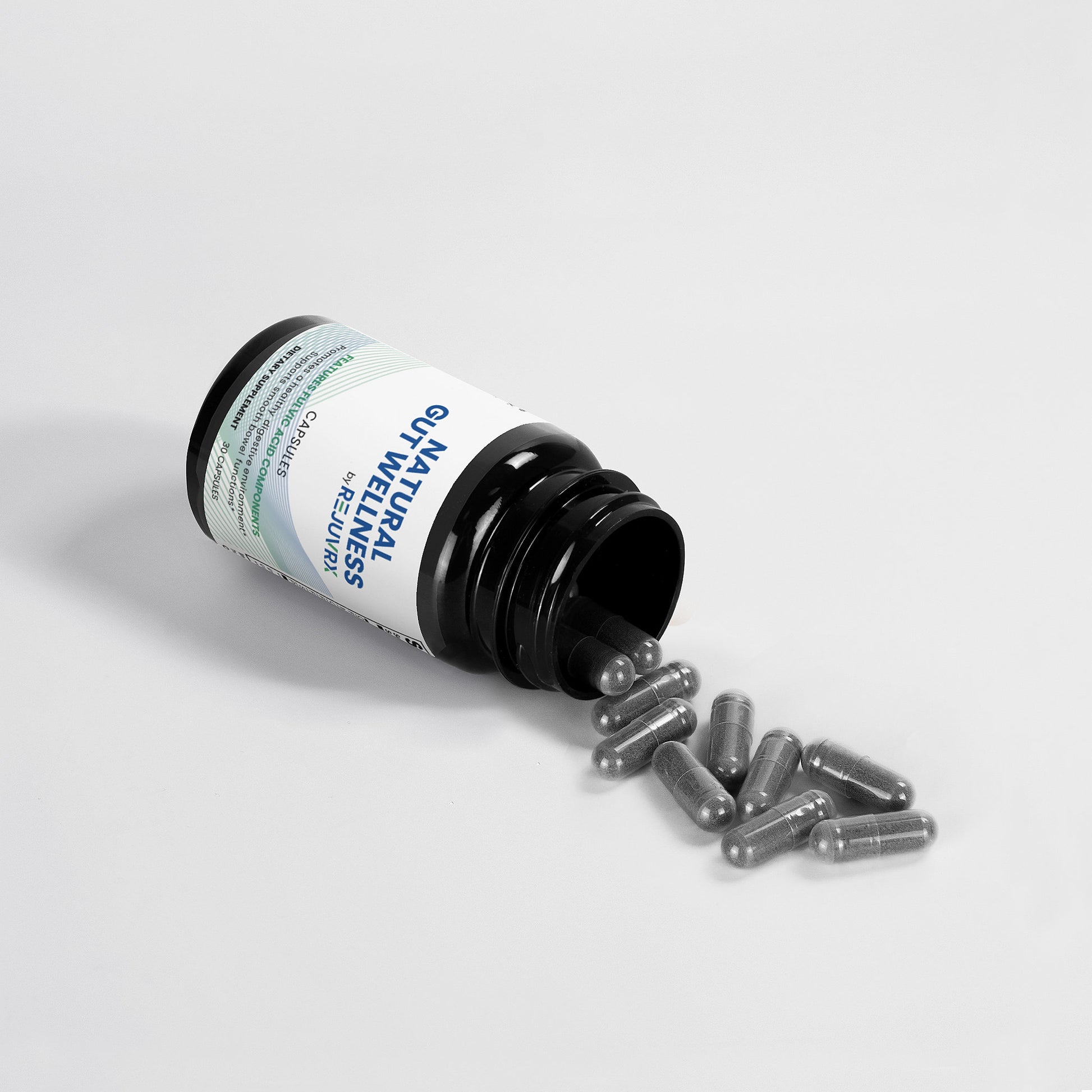 Open bottle of supplements with capsules spilling out on a light gray background