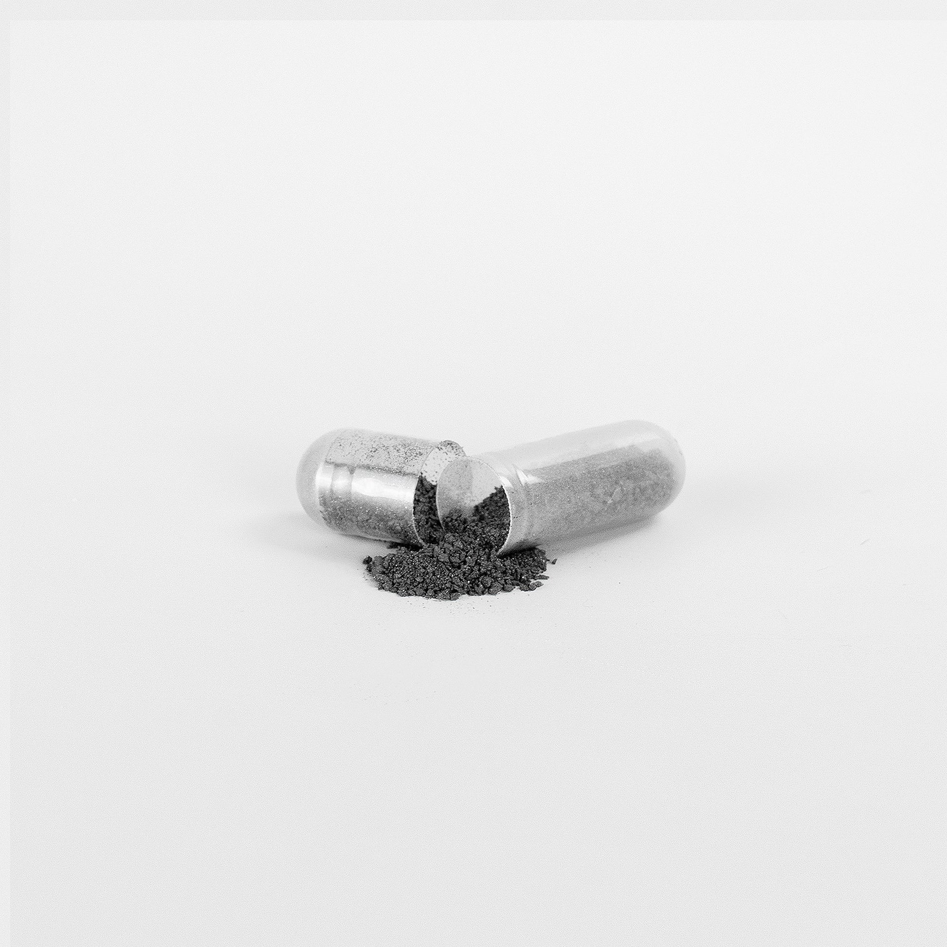 Silver capsule with black powder on a white background