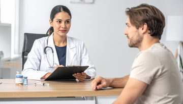 Doctor in a white coat with a stethoscope talking to a patient in a medical office.