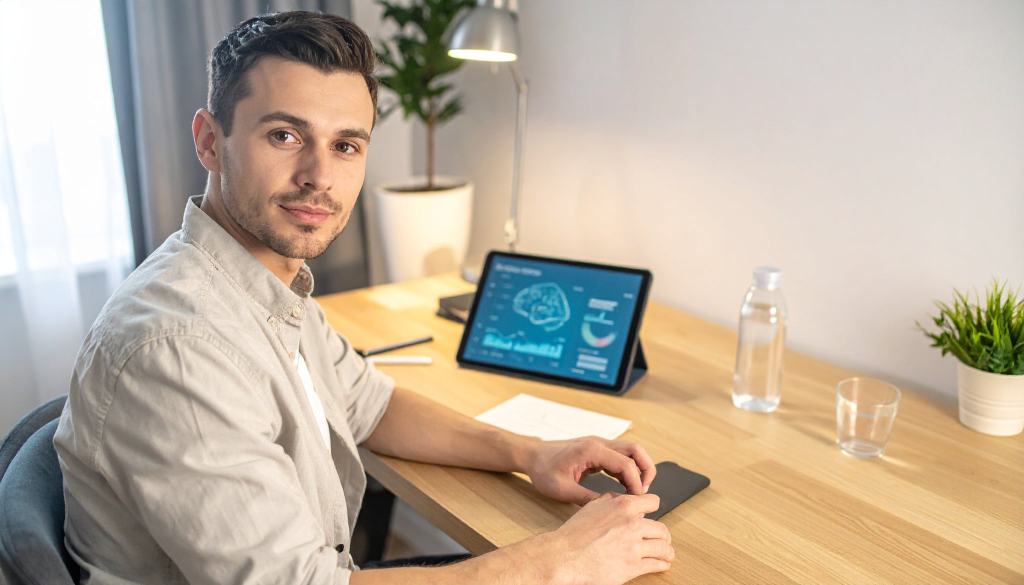 Man sitting at a desk with a tablet displaying a brain diagram