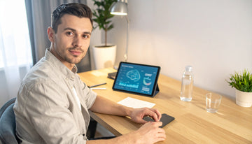 Man sitting at a desk with a tablet displaying a brain diagram