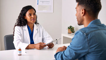 Doctor in a white coat talking to a patient in a medical office setting.