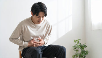 Man sitting on a chair with his hands on his stomach in a bright room.